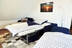 Habitació amb un llit, un escriptori i una cadira. Hi ha una làmpada a l'escriptori i un quadre a la paret.