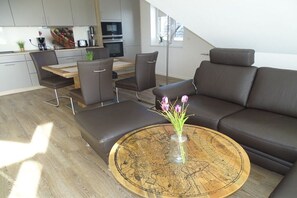 A modern living space with a dining area, a sofa, and a coffee table with a decorative globe centerpiece. - Holiday apartment with 1 bedroom (Seedorf)