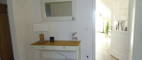 Ein Zimmer mit einem weißen Schreibtisch, einer Lampe, einem Spiegel und einer dekorativen Hirschfigur.