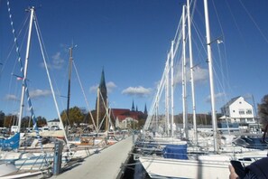 A marina with multiple sailboats docked, a church in the background, and a building with a red roof. - Holiday home with 1 bedroom (Reinsbüttel)