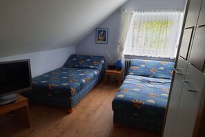 A small, single-room accommodation with two beds, a television, and a window with curtains. - Holiday home with 1 bedroom (Reinsbüttel)
