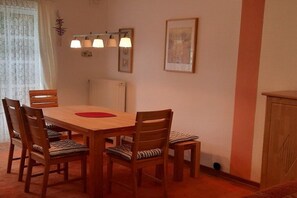 A dining area with a wooden table and chairs, a small cabinet, and a wall-mounted light fixture. - Holiday home with 1 bedroom (Reinsbüttel)