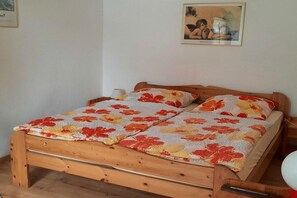 A single bed with a floral bedspread, a wooden headboard, a bedside table with a lamp, and a framed picture on the wall. - Holiday home with 1 bedroom (Reinsbüttel)
