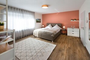 Ein modernes Schlafzimmer mit einem Bett, Nachttischen, einem Schreibtisch und einem Fenster mit Vorhängen.