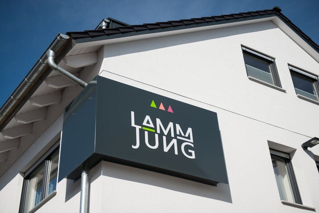 Ein Gebäude mit einem Schild, auf dem 'Lamm Jung' steht, und einem Logo darüber.