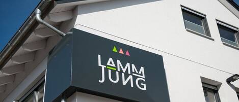 Ein Gebäude mit einem Schild, auf dem 'Lamm Jung' steht, und einem Logo darüber.