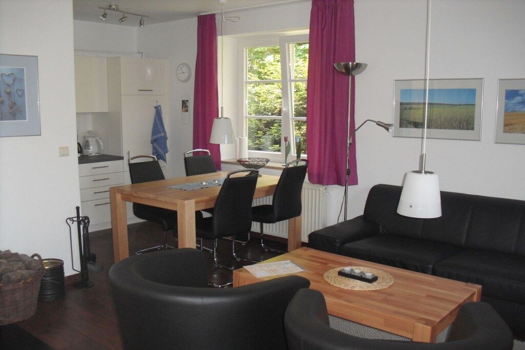 A compact living space with a dining area, a sofa, and a window with curtains.