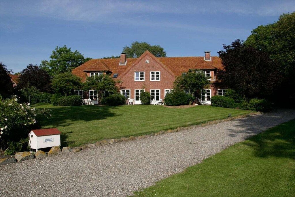 A large brick building with a symmetrical facade, multiple windows, and a well-maintained lawn in front.