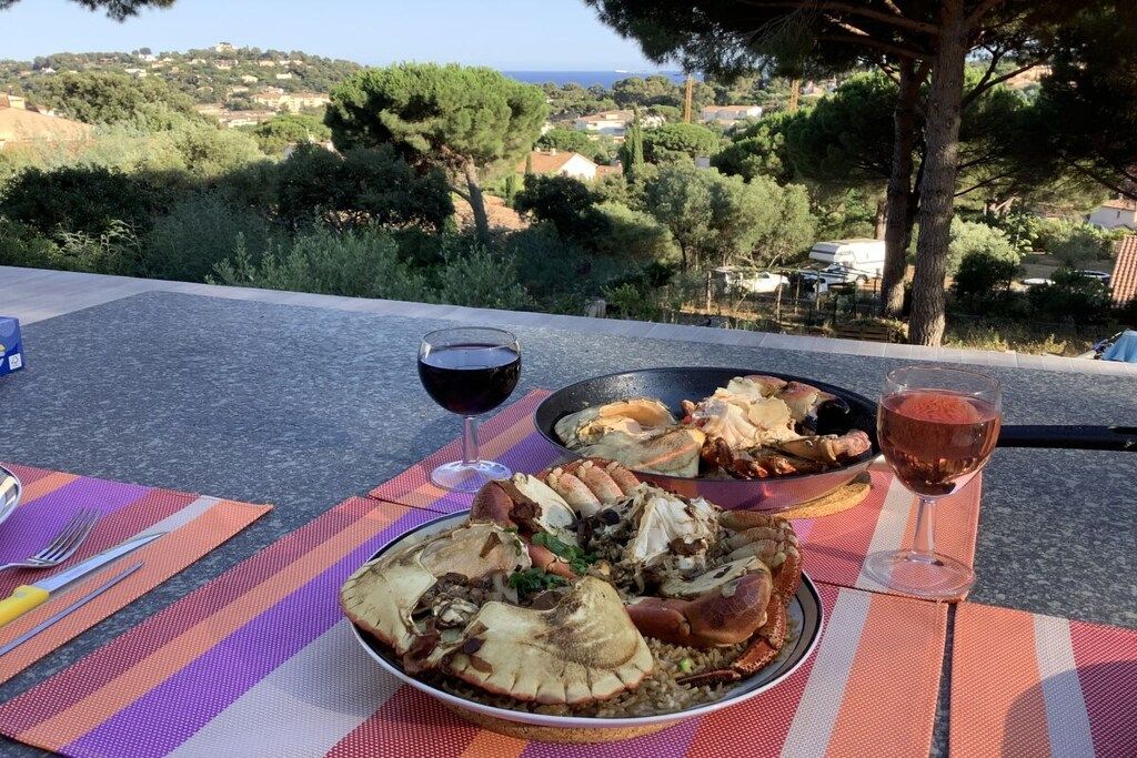 Ein Esstisch mit Meeresfrüchten und Weingläsern auf einer Terrasse mit schöner Aussicht.