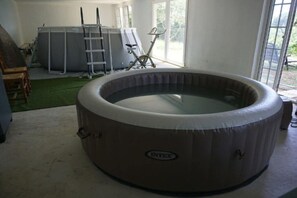 Ein Whirlpool in einem Zimmer mit einer Leiter, Fitnessgeräten und Blick ins Freie.