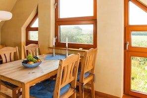 A dining area with a wooden table, chairs, and a bowl of fruit. - Holiday apartment in Nieby with swimming pool (Nieby)