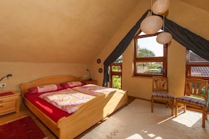 A bedroom with a wooden bed, a desk, and a chair, a window with curtains, and a hanging light fixture. - Holiday apartment in Nieby with swimming pool (Nieby)