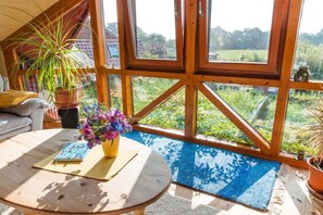 A cozy room with a large window, a round table with a book, and a potted plant. - Holiday apartment in Nieby with swimming pool (Nieby)