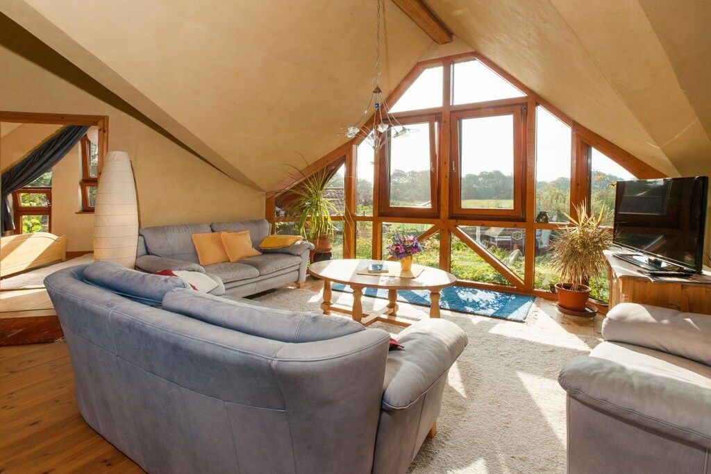 A cozy loft bedroom with a large window, a bed, and a TV.