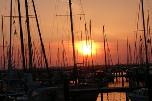 Un port de plaisance au coucher du soleil, où sont amarrés de nombreux voiliers.