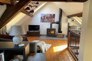 Een knus loft slaapkamer met een schuine kap, een open haard, een televisie en een comfortabele zithoek.