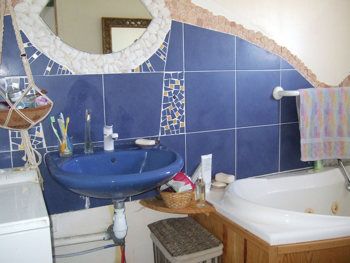 A bathroom with a blue sink, a white bathtub, and a mirror above the sink.