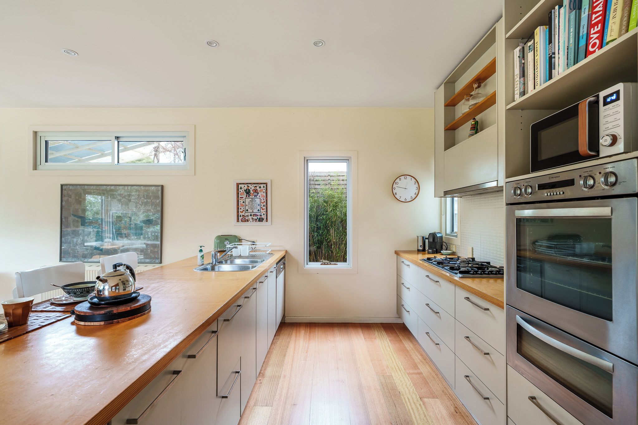 Una cocina moderna con encimera de madera, electrodomésticos de acero inoxidable y ventana con vistas a zonas verdes.