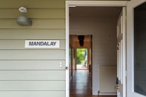 A hallway with a sign reading 'MANDALAY' on the wall, a door on the right, and a window on the left.