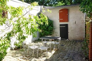 A courtyard with a table and chairs, a black door, and a red shutter on a wall. - Holiday home in Tangermünde with Wi-Fi (Tangermünde)