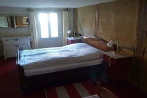 A bedroom with a bed, a bedside table with a lamp, a dresser, and a mirror on the wall. - Holiday home in Tangermünde with Wi-Fi (Tangermünde)