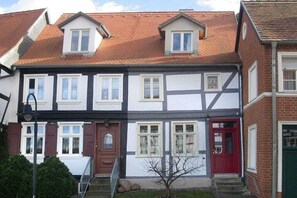 Ein zweistöckiges Haus mit Satteldach, Dachfenstern und einer roter Tür.