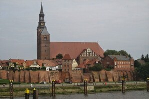 Ein historisches Gebäude mit einem markanten Turm und einer hohen Backsteinmauer.