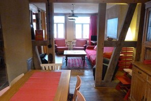 Une pièce étroite comprenant une table à manger, des chaises, un canapé et un téléviseur.