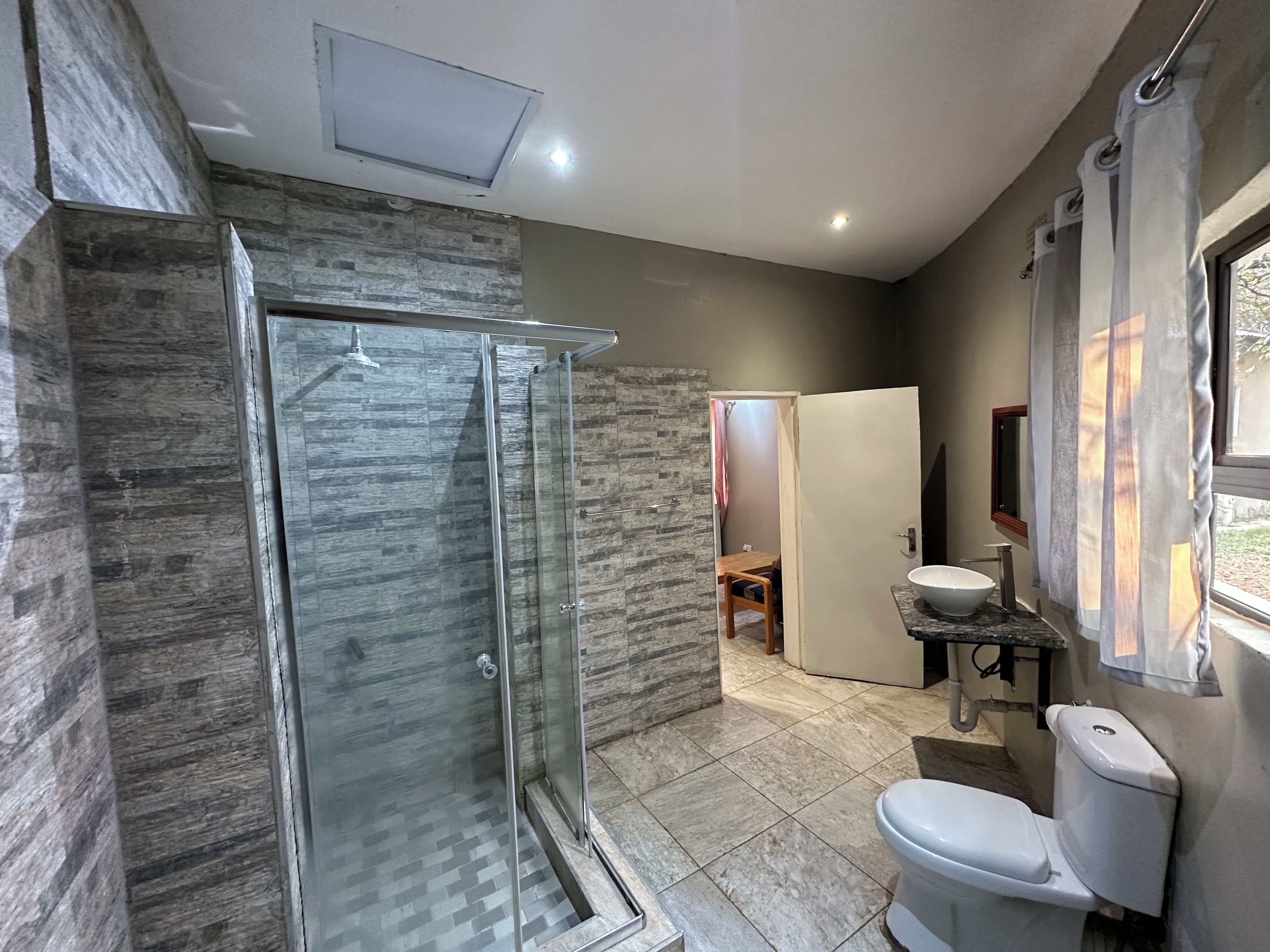 A modern bathroom with a glass-enclosed shower, a toilet, and a sink.