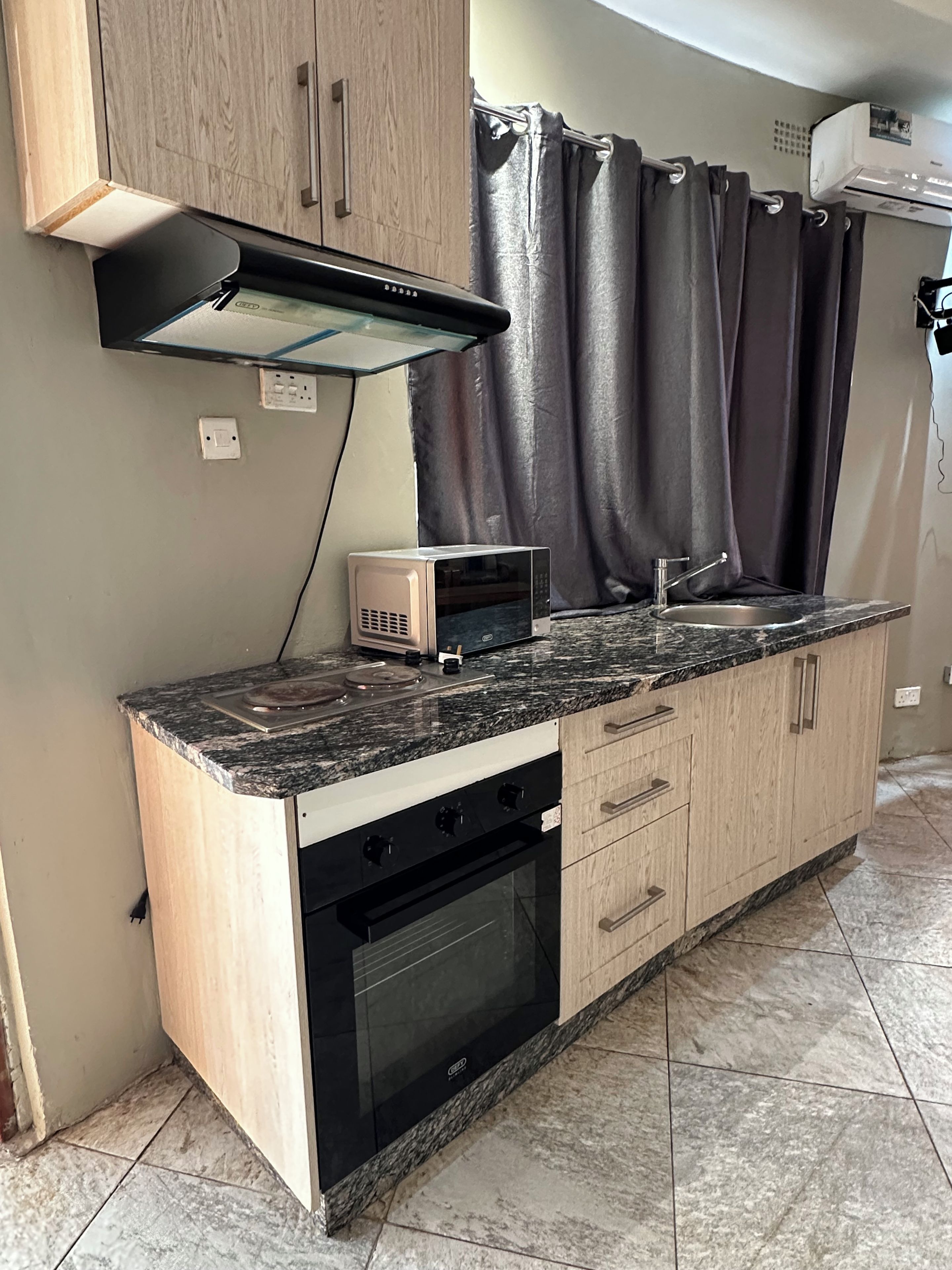 A kitchen with a microwave, oven, and a sink.