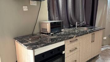 A kitchen with a microwave, oven, and a sink.