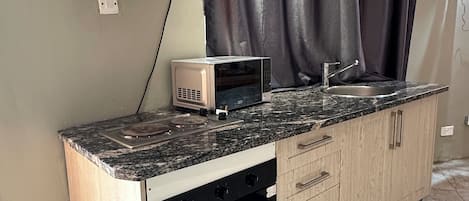 A kitchen with a microwave, oven, and a sink.