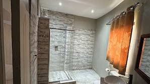 Ein modernes Badezimmer mit einer gläsernen Duschkabine, einem Waschtisch mit einer Schüssel und einer Toilette.