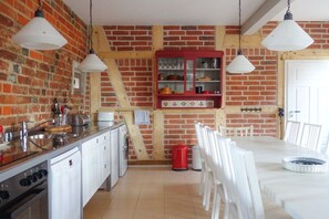 A kitchen with a brick wall, wooden beams, white cabinets, and hanging pendant lights. - Holiday home in Tangermünde with Wi-Fi (Tangermünde)