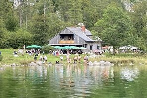 A rustic wooden building with a balcony, surrounded by a lake and a crowd of people. - Holiday home with 1 bedroom (Altaussee)
