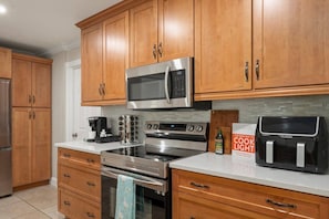A kitchen with wooden cabinets, stainless steel appliances, a coffee maker, and a cookbook. - Siesta Sands Paradise 4BR 3BA Sleep 16 (Sarasota)