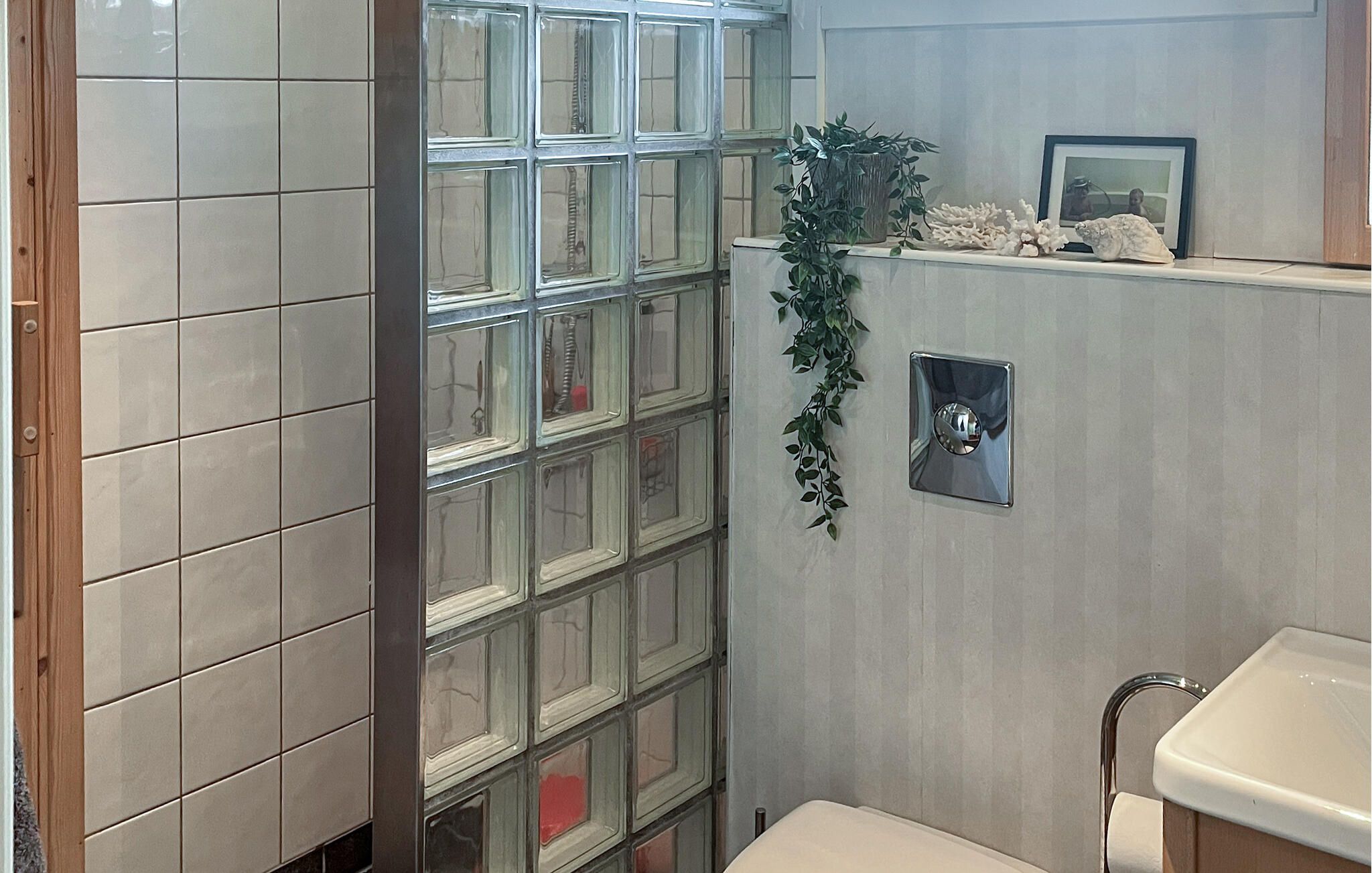 Une salle de bain avec une douche à parois de verre, un lavabo et un luminaire fixé au mur.