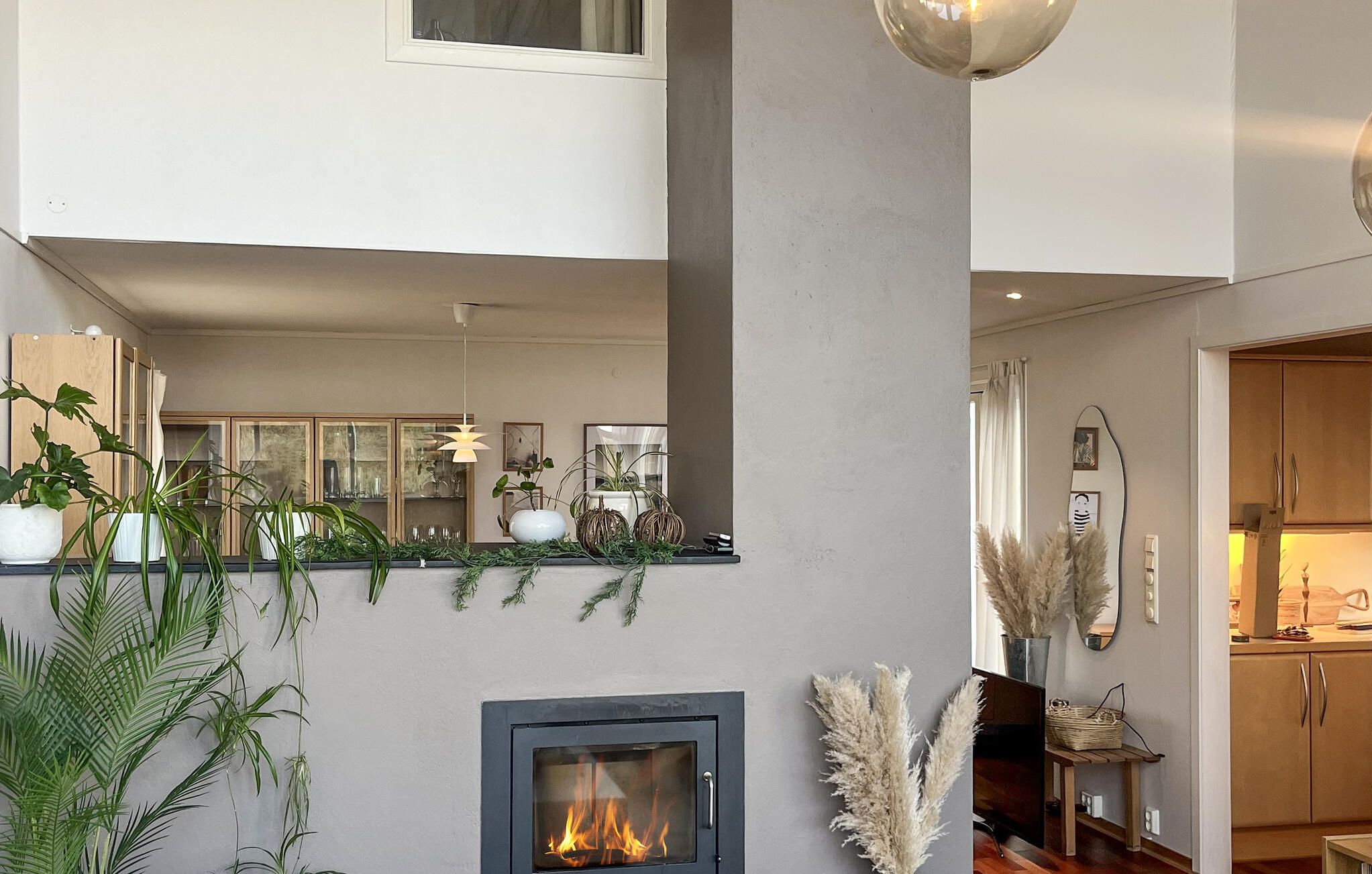 A modern living room with a fireplace, a dining area with a glass-top table, and a kitchen area with wooden cabinets.