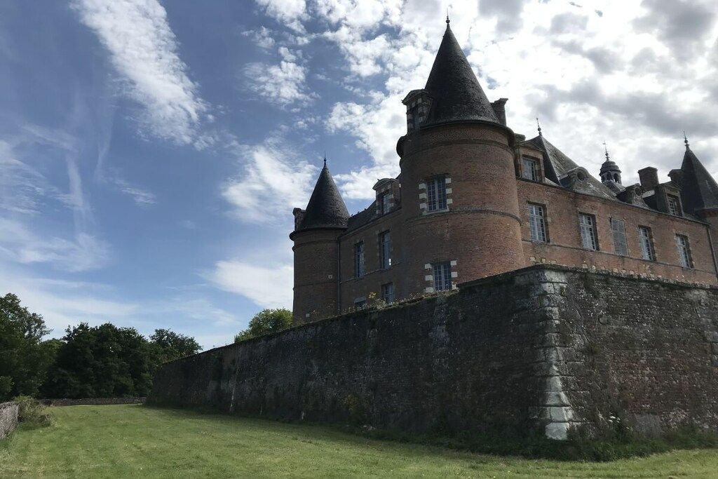 Un edificio grande e histórico con múltiples torres y una muralla fortificada.