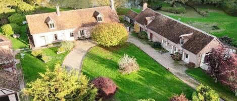 A traditional estate with multiple buildings, a well-maintained lawn, and a pond.