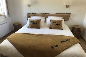 Ein Bett mit weißer Bettwäsche und braunen Zierkissen, zwei Nachttische und ein Holz-Kopfteil.