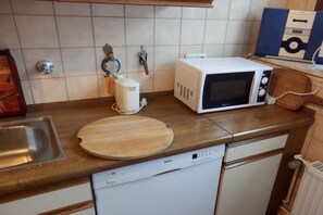A kitchen with a Bosch dishwasher, a white microwave, a wooden cutting board, and a stainless steel sink. - Just outside Hamburg 4 (Reinbek)