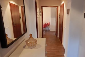 A hallway with a wooden floor, a white wall, and a door at the end. - Just outside Hamburg 4 (Reinbek)