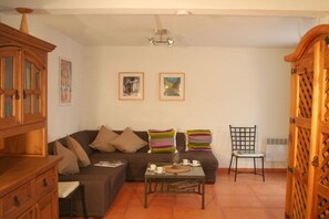 A living room with a sofa, a coffee table, a cabinet, and two framed pictures on the wall. - Holiday home in Gruissan with swimming pool (Gruissan)