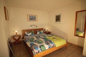 A bedroom with a bed, two bedside tables, a mirror, and two wall-mounted lamps. - Holiday home in Gruissan with swimming pool (Gruissan)