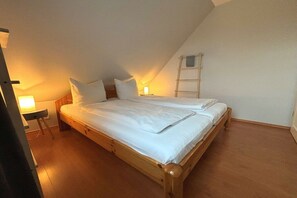 A single bed with a wooden frame in a room with sloped ceilings. - Holiday home with 3 bedrooms (Schönberg Brasilien)
