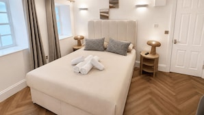 A hotel room with a large bed, two bedside tables, a window with curtains, and a door. - Nestoya House (London)