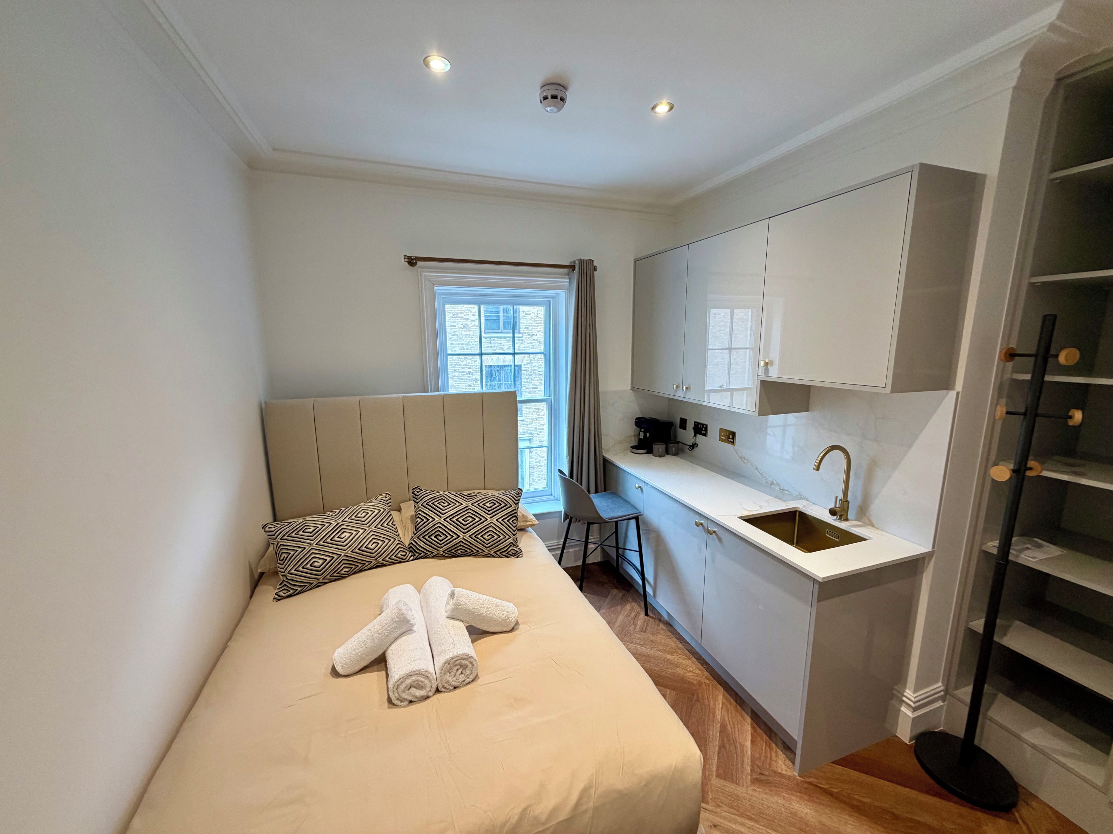 Un dormitorio pequeño con cama, una kitchenette y una ventana.