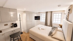 A hotel room with a bed, a desk, a chair, a television, and a window. - Nestoya House (London)