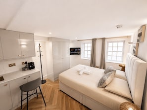 Hotellihuone, jossa on sänky, työpöytä, tuoli, televisio ja ikkuna.